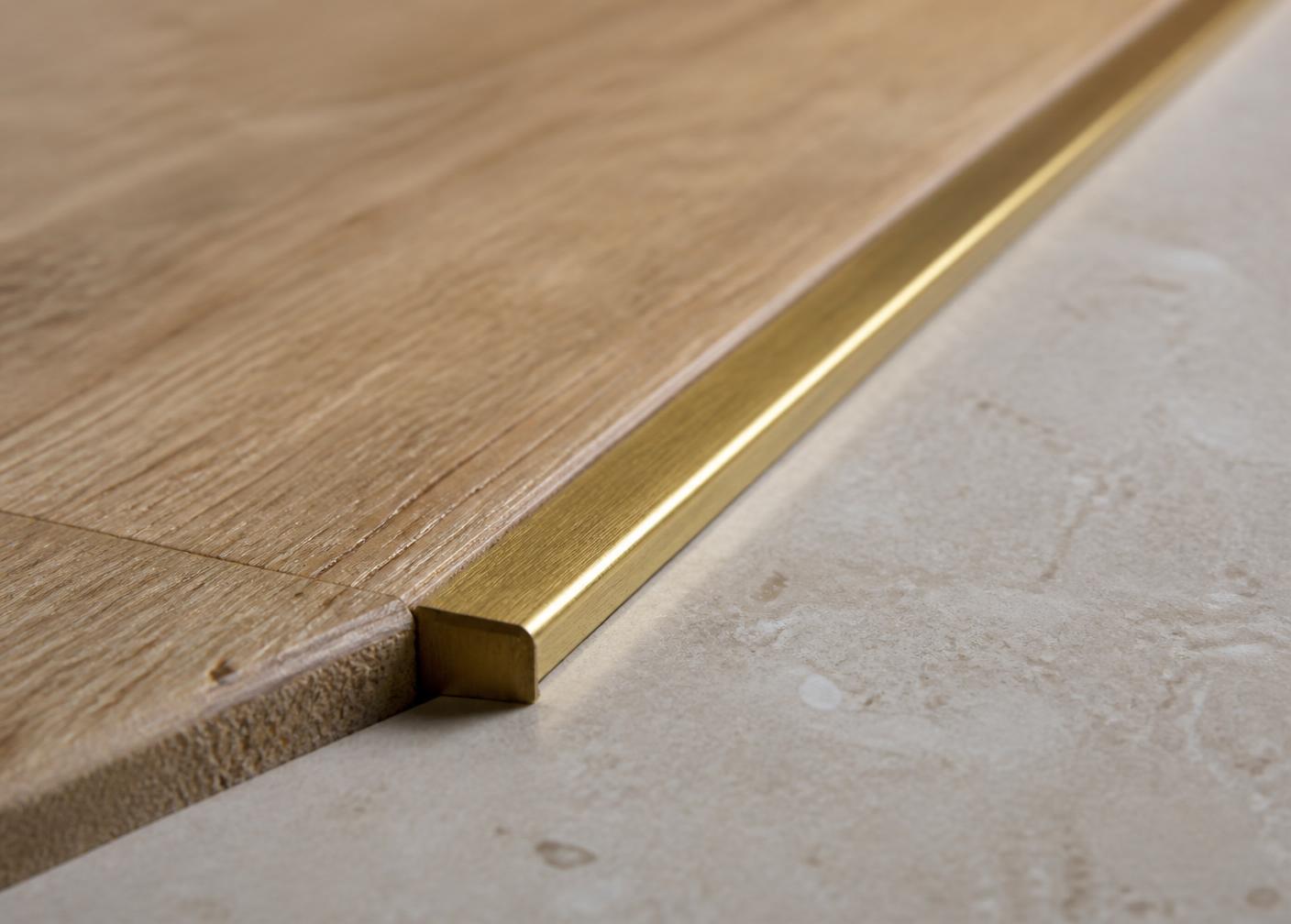 Raccordo tra parquet in rovere e pietra con profilo in ottone spazzolato